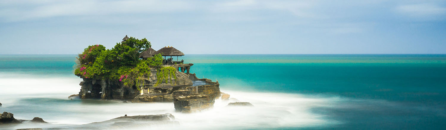 Ngôi đền Tanah Lot được xây trên đỉnh của một hòn đá khổng lồ giữa bốn bề biển xanh, sóng vỗ rì rầm và cách bờ biển Pura Tanah Lot bởi một lối đi nhỏ. Khi thủy triều xuống, các tín đồ Hindu xếp hàng dài, bước trên những phiến đá tiến vào dâng lễ, những người ngoại đạo vào lễ cũng được phết lên tóc một ít nước thánh, đính lên trán những hạt gạo, cài lên tóc một bông sứ trắng.